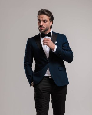 Smokinli zarif bir iş adamı gri arka planda el ele yürümeye çalışıyor.