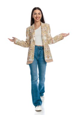 Mavi kot pantolonlu mutlu bir kadın kollarını açıyor ve gülümsüyor ve beyaz arka planda yürüyor. 