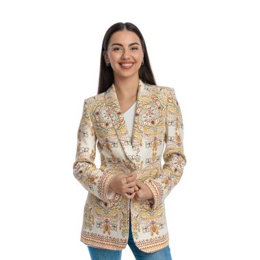 Beyaz arkaplan önünde ceketi kapatırken ileriye bakıp gülümseyen mutlu genç bir kadının portresi