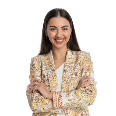 Güzel sıradan bir kızın portresi kollarını kavuşturuyor ve beyaz arka planda gülümserken ileriye bakıyor.