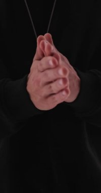 Çivili güneş gözlüklü, avuçlarını ovuşturan ve gri arka planda ileriye bakan sıradan bir adamın videosunu çek.