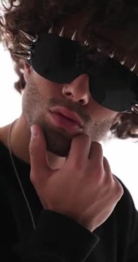 Gri arka planda çivili güneş gözlüklü havalı adamın tensel olarak çenesine ve boynuna dokunduğu videoyu kapat.