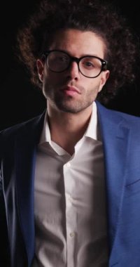 Gözlüklü, çekici ve zarif bir adam. Önüne bakıyor, çenesine dokunuyor ve siyah arka plan üzerinde düşünüyor.