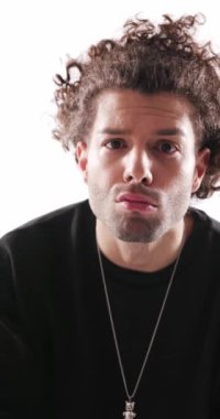 Siyah kazaklı çekici genç adam sessiz bir jest yapıyor, ileriye bakıyor, gri arka planda başını sallıyor ve kollarını kavuşturuyor.