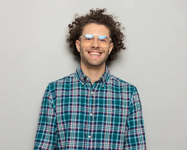 チェッカーのシャツを着たメガネでワクワクするカジュアルな男の肖像画 灰色の背景の前にポーズしながら幸せで笑っている — ストック写真