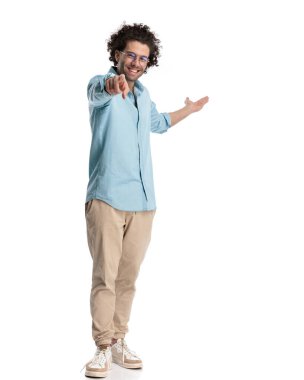 Yakışıklı, sıradan bir adam bir seçim yapmak için işaret ediyor ve beyaz arka planda dururken taraf olmayı öneriyor.