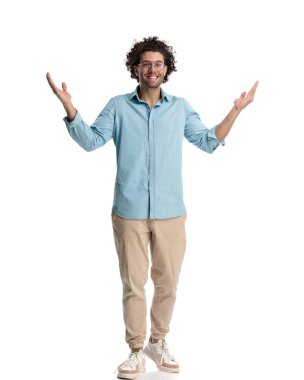 Genç, sıradan bir adam, izole edilmiş arka planda dururken elleriyle bir hoş geldin jesti yapıyor.