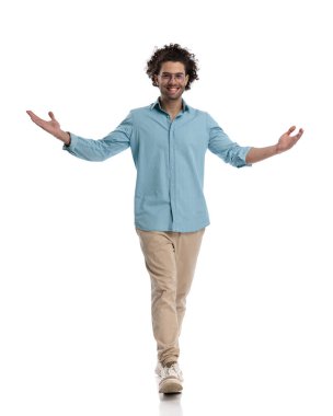 Mavi gömlekli sıradan bir adam beyaz arka planda hoş geldin jesti yapıyor.