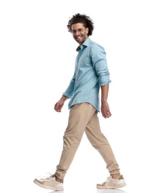 Beyaz arka planda yürüyen neşeli genç adamın yan görünüşü