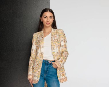 Ceketi cebinde güzel bir genç kız karanlık ve aydınlık arka planda dururken poz veriyor. 