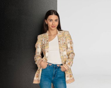 Kotların cebinde el ele tutuşan, koyu ve açık gri arka planda poz veren mutlu, sıradan bir kız. 