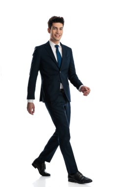 Donanma mavisi takım elbiseli mutlu ve zarif bir iş adamının beyaz arka planda gülümseyen ve yürüyen tüm vücudu.