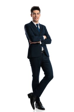 Donanma mavisi takımlı, kollarını kavuşturup beyaz arka planda duran mutlu, zarif iş adamının tüm vücudu. 