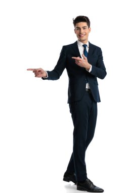 Beyaz arka planda yürürken parmaklarını sağa sola gösteren ve yolu gösteren mutlu zarif adamın yan görünümü