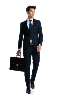 Bavullu, lacivert takım elbiseli, beyaz arka planda yürümeye çalışan seksi, zarif bir adam.