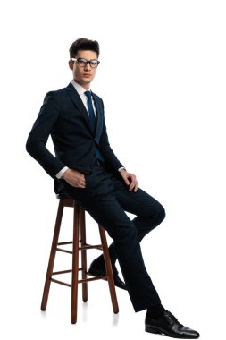 Kendine güvenen, gözlüklü, el ele tutuşan ve beyaz arka planda oturan zarif bir adamın yan görüntüsü.