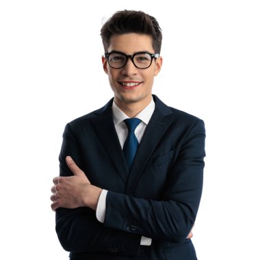 Gözlüklü, kollarını kavuşturup gülümseyen ve stüdyoda beyaz arka planda poz veren yakışıklı bir adamın portresi.