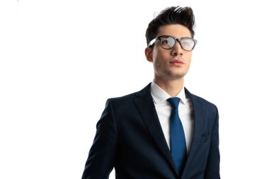 Lacivert takımlı genç, zeki, zarif bir adam. Beyaz arka planda bakıp düşünüyor. 