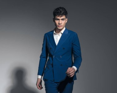 Gri arka planda yürüyen seksi model adamın yakın çekimi.