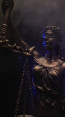 Eşitlik ve denge kavramını gösteren bir ölçek taşıyan bronz heykel yasasının dikey videosu, polis ışıkları siyah arkaplanda dumanla yanıyor