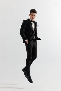 Gri arka planda elleri havada duran çekici bir iş adamı.