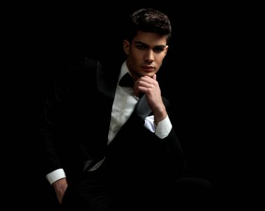 Siyah takım elbiseli ve kravatlı dalgın işadamlarının siyah arka planda el ele oturduğu yakın plan.