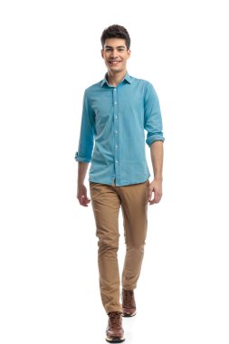 Mavi gömlekli ve kot pantolonlu neşeli bir adam beyaz arka planda öne çıkıyor.