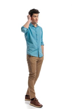 Kafası karışmış sıradan bir adam elini cebine atarak öne çıkıyor ve kafasını beyaz arka plana sürtüyor.