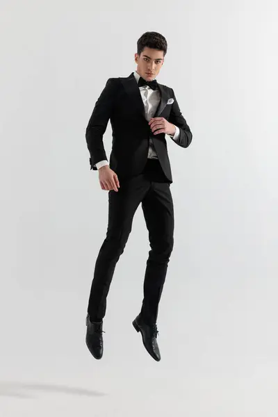 Sexy Fashion Man Black Tux Jumping Air While Buttoning His Лицензионные Стоковые Изображения