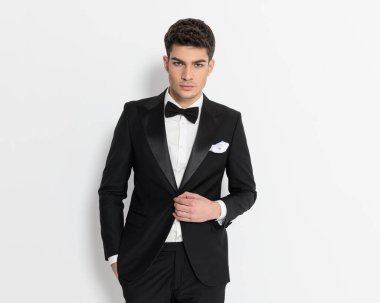 Havalı, şık bir iş adamının portresi. Siyah smokini koyu gri arka planda ayarlıyor. 