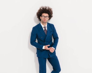 Zarif lacivert takımlı, avuçlarını ovuşturan ve gri arka planda ileriye bakan kendine güvenen seksi adamın portresi.