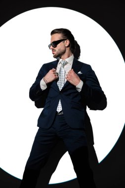 Spot ışıkları önünde şık bir takım elbise giyen yakışıklı bir gencin portresi.