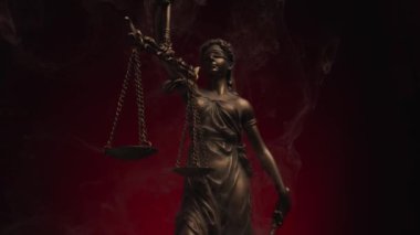 Gözleri bağlı mermer heykel adalet tanrıçasını temsil ediyor koyu kırmızı arka planda bir denge tutuyor