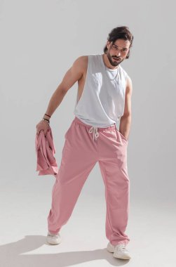 Formda vücudunun cebinde el ele tutuşan ve gri arka planda yürüyen sporcunun tam vücut resmi.