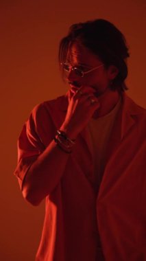 Şehvetli moda adamı çeneye dokunuyor, düşünüyor, saçlarını ayarlıyor ve yan tarafa bakıyor, kırmızı ışıkta el ele tutuşuyor.