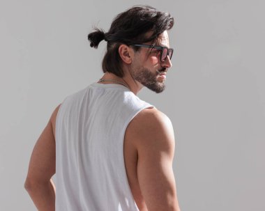 Güneş gözlüklü, uzun saçlı ve gri arka planda poz veren seksi sakallı adamın dikiz aynası.