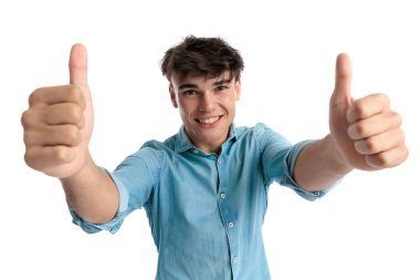 Mavi kot gömlekli mutlu bir adam başparmak hareketi yapıyor ve kazananı beyaz arka planda gülümserken kutluyor.