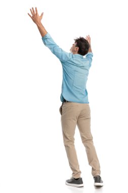 Çaresiz genç bir öğrenci ellerini gökyüzüne kaldırıyor ve beyaz arkaplan önündeki yüce bir güçten rehberlik istiyor ya da cevaplar arıyor.