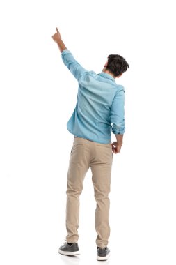 Arkadan gökyüzünü işaret eden genç adam beyaz arkaplan önünde bir farkındalık anını kutluyor.