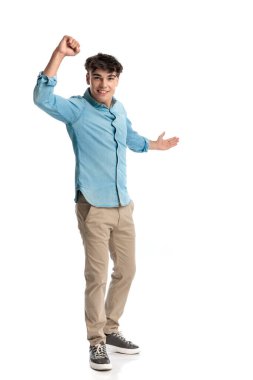 Kot gömlekli mutlu genç bir öğrenci. Kutlamada yükseğe yükseldi ve diğerlerini zaferinin sevincine katılmaya teşvik etti.