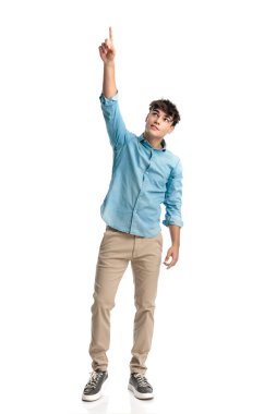 20 'li yaşlarda genç bir öğrenci yukarı bakıyor, parmağını gökyüzüne kaldırıyor ve beyaz arka plandaki başarıya şükrediyor.