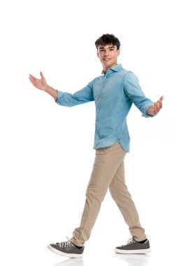 Mavi gömlekli mutlu genç adamın yan görüntüsü kollarını açıyor ve beyaz arka planda konukları selamlıyor.