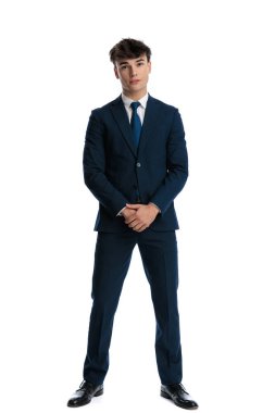 Lacivert takımlı havalı genç adam el ele tutuşuyor ve beyaz arka planın önünde duruyor.