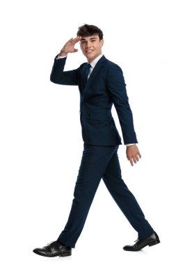 Beyaz arka planda yüzünde kocaman bir gülümsemeyle yürüyen zarif genç iş öğrencisinin ve askeri selamlaşmanın yan görüntüsü.