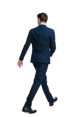 Zarif lacivert takım elbiseli genç işadamı beyaz arka planda yürümeye çalışıyor.