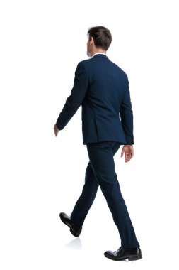 Lacivert takım elbiseli zarif genç iş adamının beyaz arkaplan önünde kendine güvenle yürürken tüm vücudu.