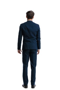 Beyaz arka planda duran lacivert takım elbiseli zarif genç adam.