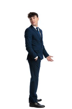 Zarif genç işletme öğrencisi cebinde, arkasına bakıyor ve beyaz arka planda konuşuyor.