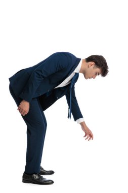 Beyaz arka planda yerden bir şey alıp büken genç bir işletme öğrencisinin yan görüntüsü