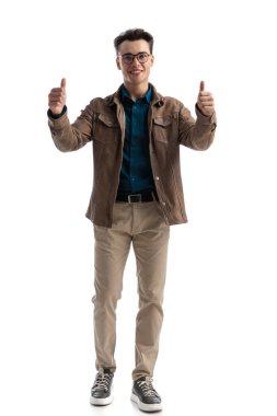 Deri ceketli akıllı sıradan bir adam gülümserken ve beyaz arka planda dikilirken baş parmak işareti yapıyor.